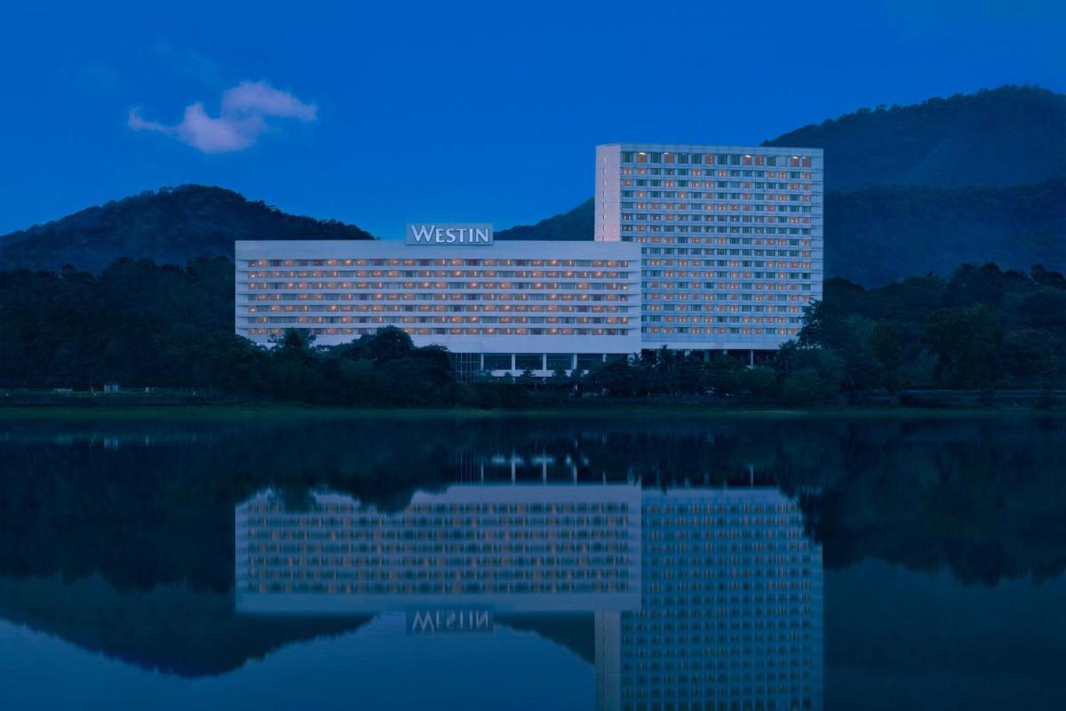 a building with a reflection in a body of water at The Westin Mumbai Powai Lake in Mumbai