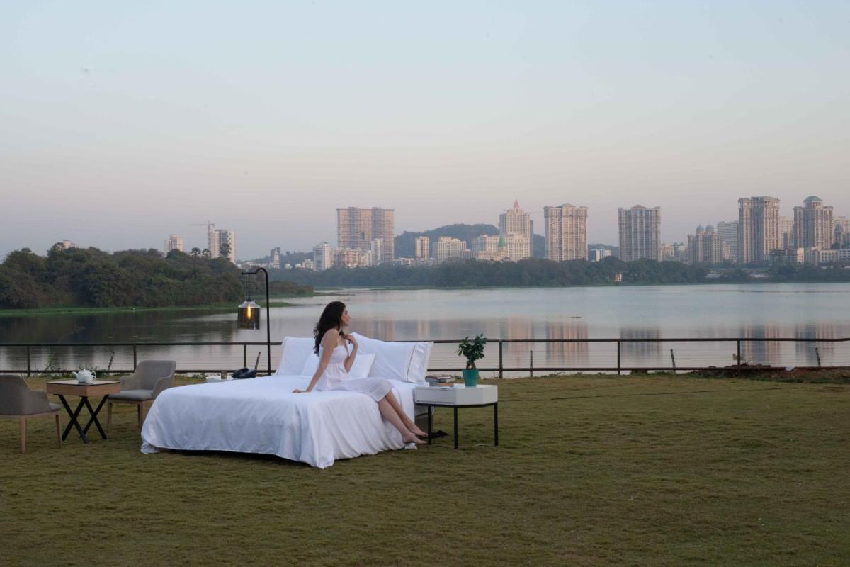 a woman in a white dress sitting on a bed at The Westin Mumbai Powai Lake in Mumbai