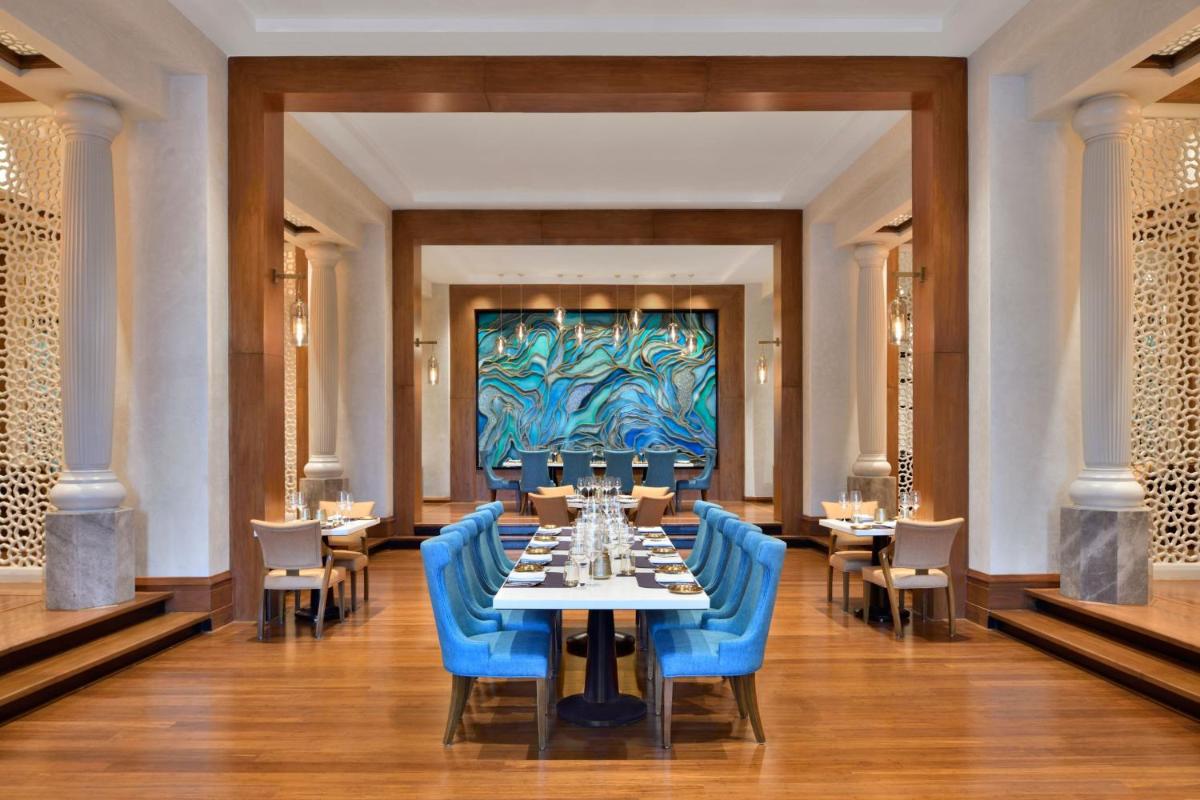 a dining room with a table and blue chairs at The Westin Mumbai Powai Lake in Mumbai