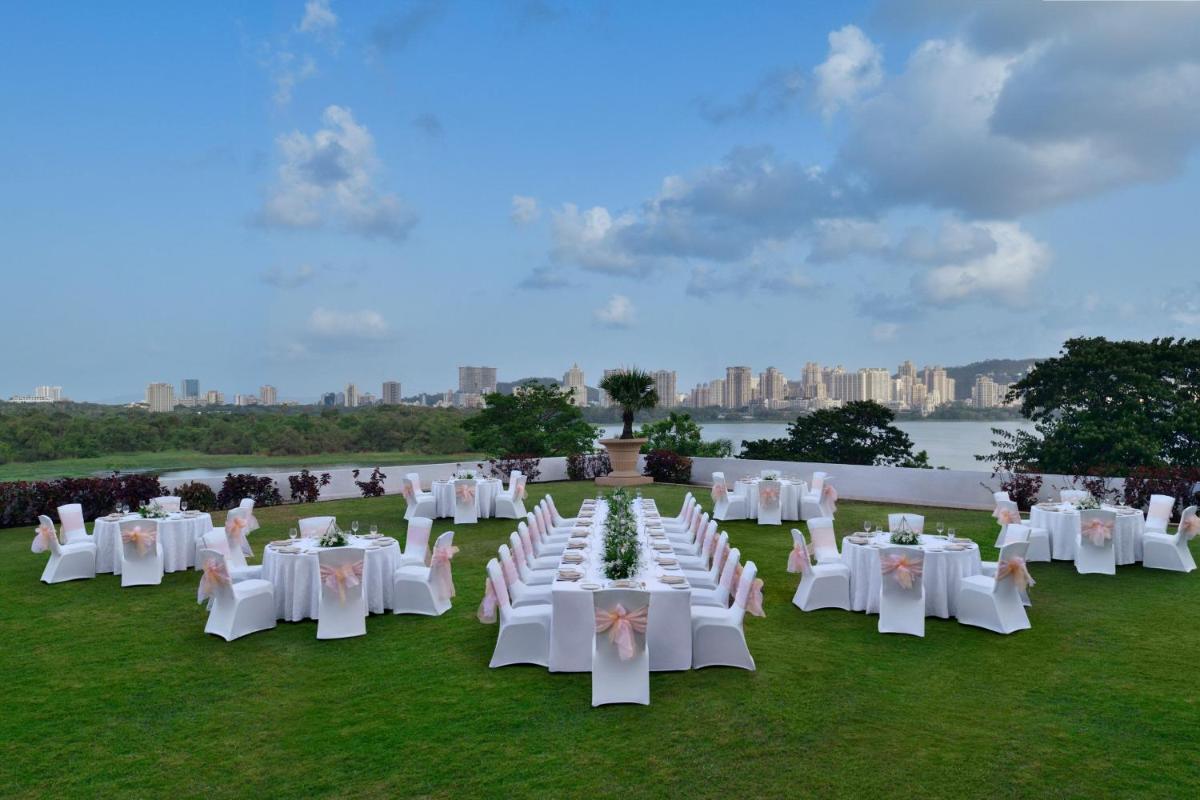 a group of white tables and chairs on a field at The Westin Mumbai Powai Lake in Mumbai