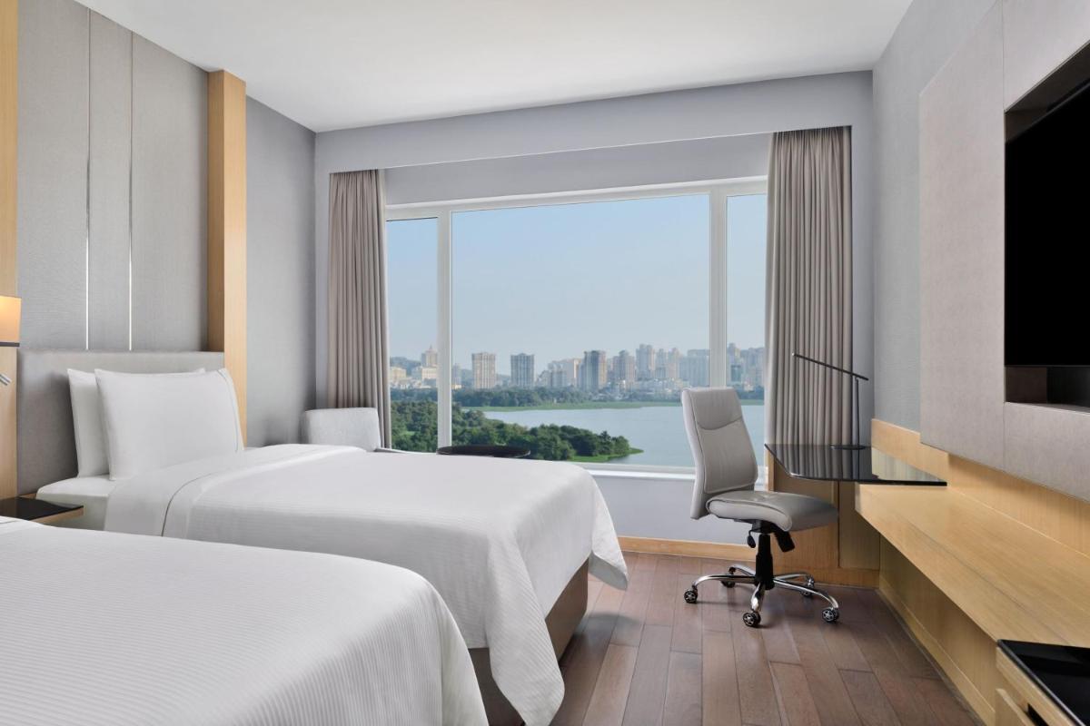 a hotel room with two beds and a large window at The Westin Mumbai Powai Lake in Mumbai