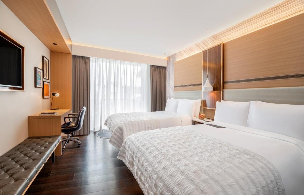 a hotel room with two beds and a television at Le Meridien Goa, Calangute in Calangute a hotel room with two beds and a television at Le Meridien Goa, Calangute in Calangute