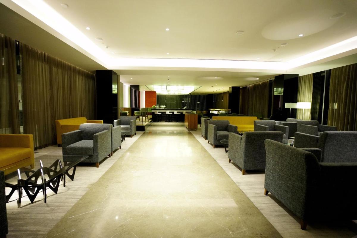 a waiting area with chairs and tables in a building at BLVD Club - Near BENGALURU AIRPORT in Bengaluru
