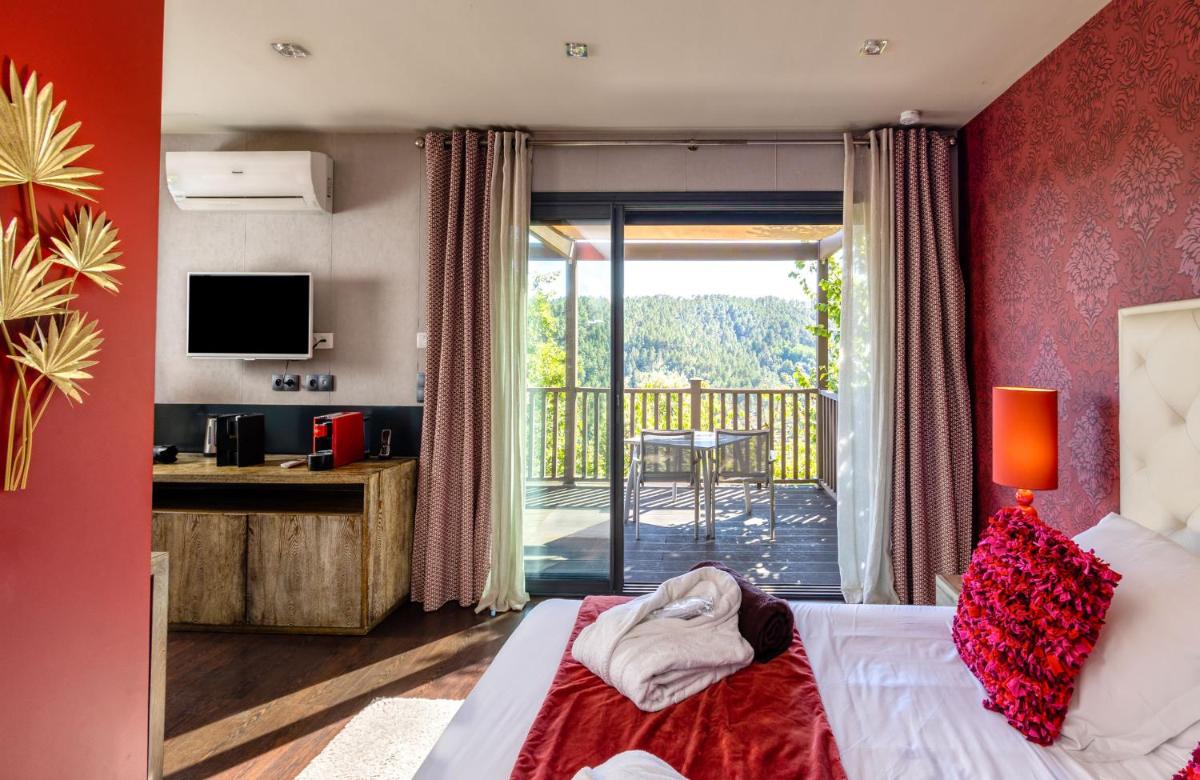 une chambre d'hôtel avec un lit et un balcon dans l'établissement Domaine de Chalvêches Hôtel SPA 4*, à Faugères