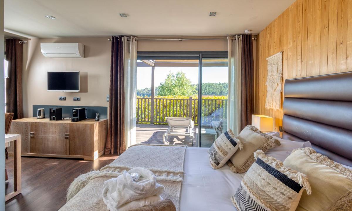 une chambre d'hôtel avec un lit et un balcon dans l'établissement Domaine de Chalvêches Hôtel SPA 4*, à Faugères