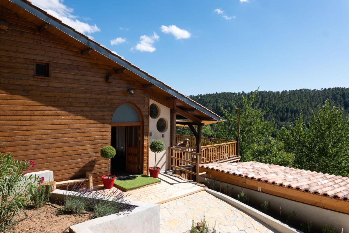 une maison en bois avec un porche et une terrasse dans l'établissement Domaine de Chalvêches Hôtel SPA 4*, à Faugères