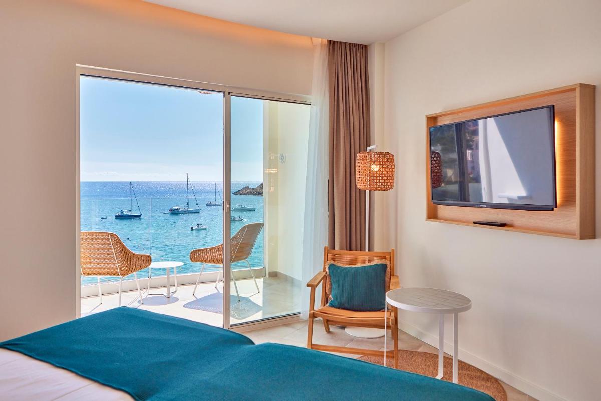 Un dormitorio con una cama y vista al mar. en Universal Hotel Aquamarin, en Sant Elm