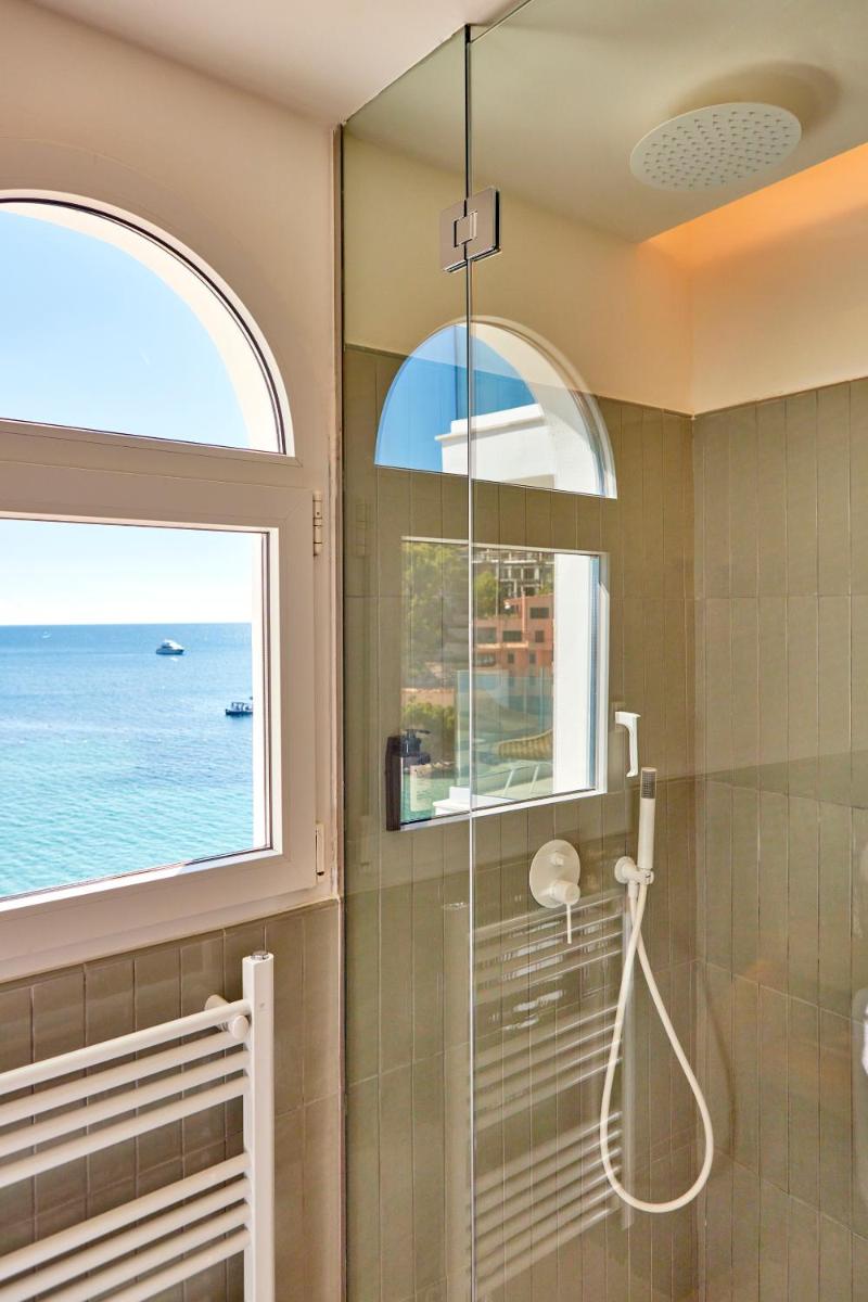 Un baño con ducha y ventana. en Universal Hotel Aquamarin, en Sant Elm