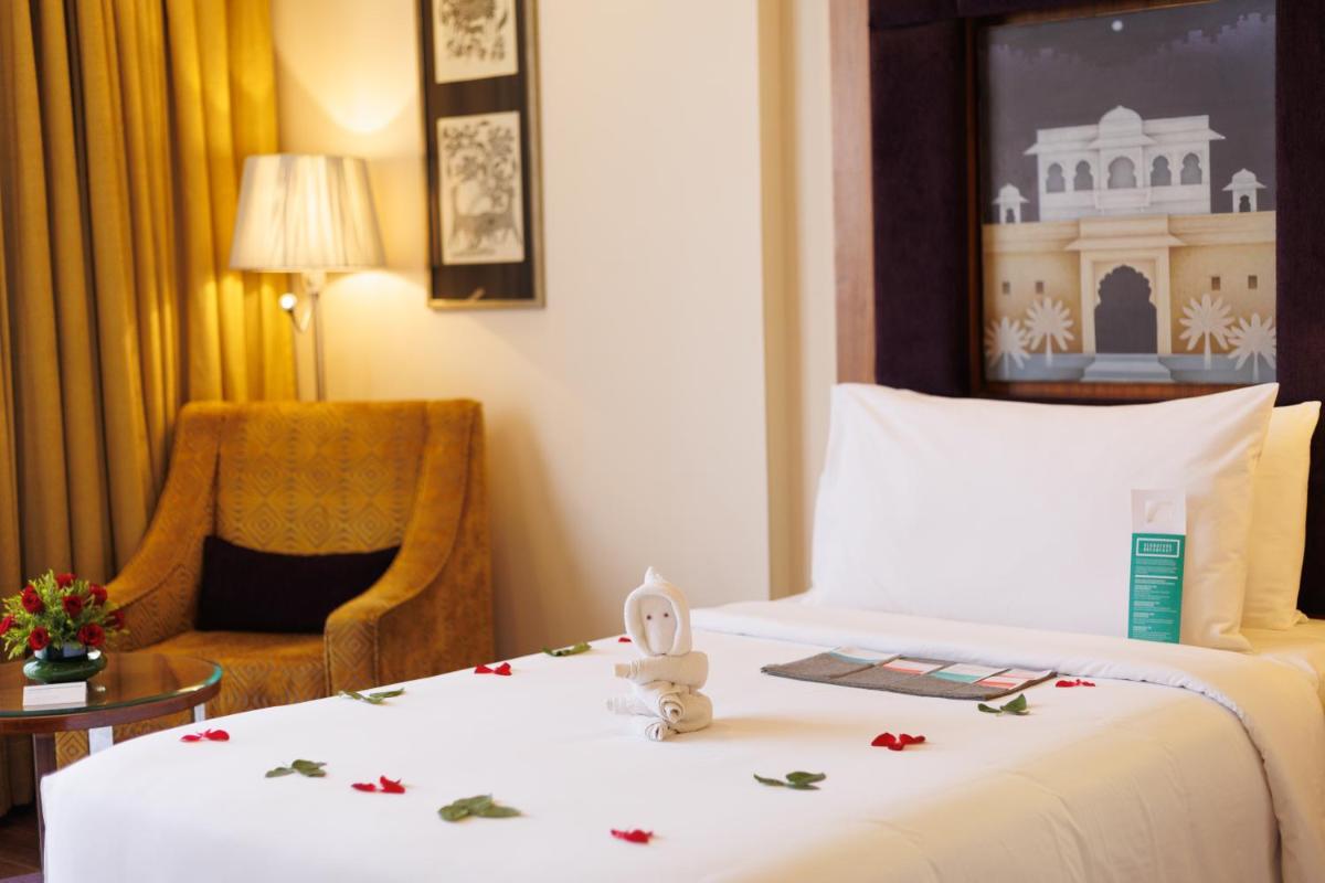 a hotel room with a bed and a chair at Le Meridien Jaipur Resort & Spa in Jaipur
