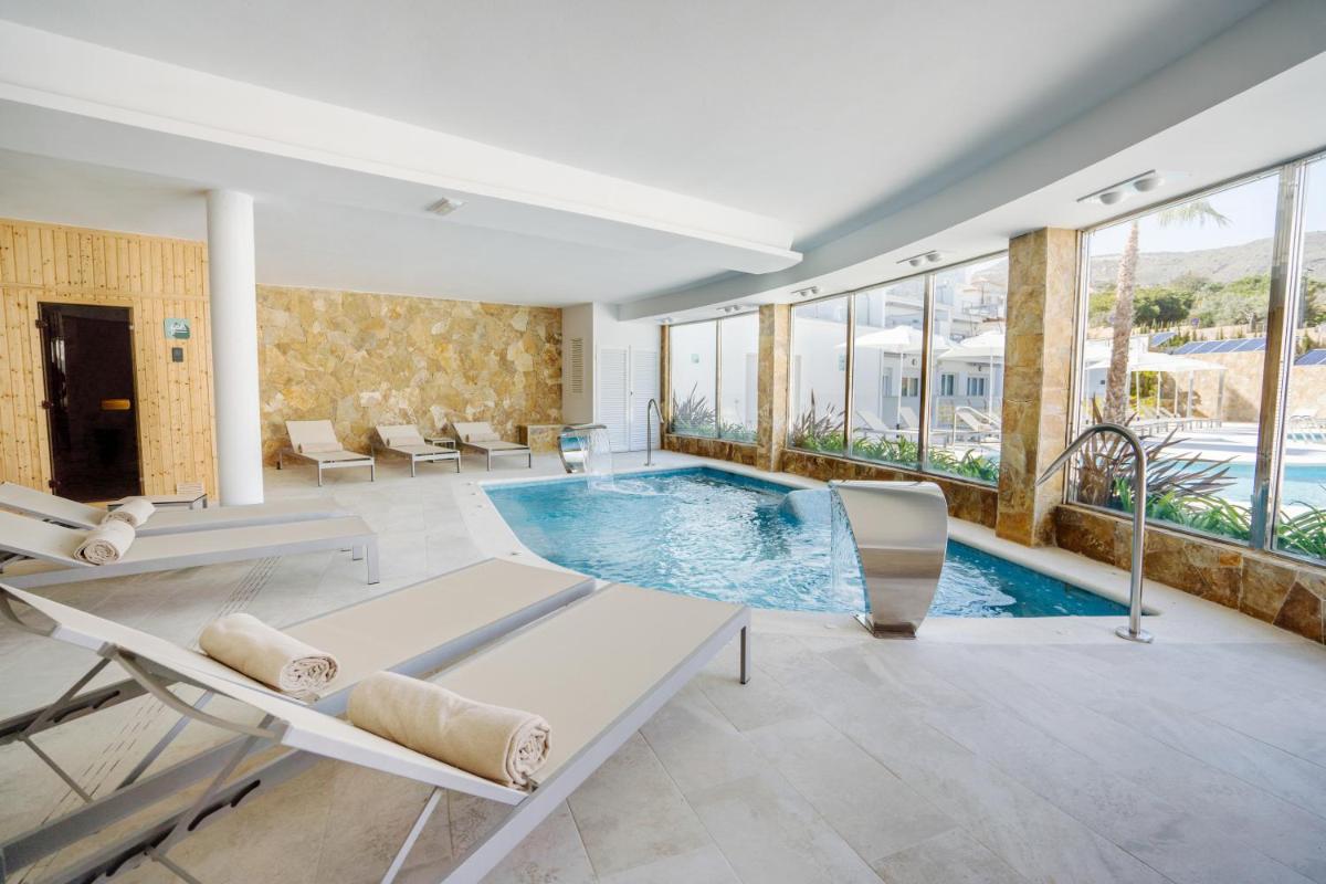 Una piscina en una habitación con sillas y ventanas. en Dormio Resort Costa Blanca Beach & Spa, en El Campello