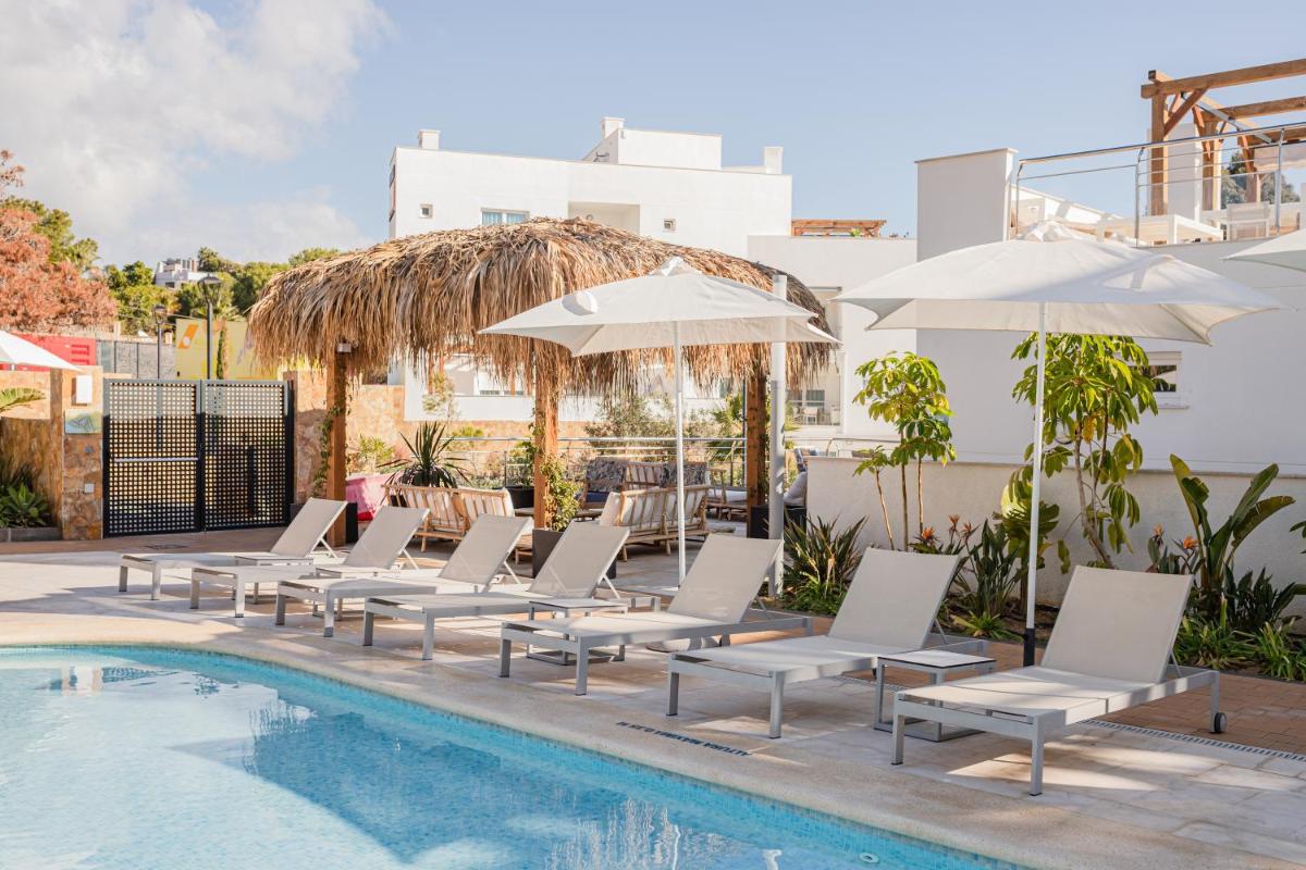 Una fila de sillas blancas y sombrillas junto a una piscina. en Dormio Resort Costa Blanca Beach & Spa, en El Campello