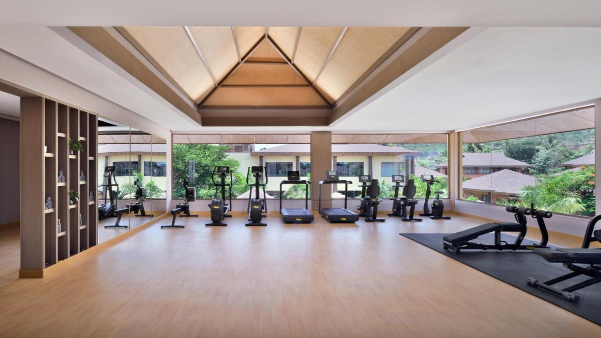 a gym with treadmills and exercise equipment in a building at Mulberry Shades Bengaluru Nandi Hills - a Tribute Portfolio Resort in Bengaluru a gym with treadmills and exercise equipment in a building at Mulberry Shades Bengaluru Nandi Hills - a Tribute Portfolio Resort in Bengaluru