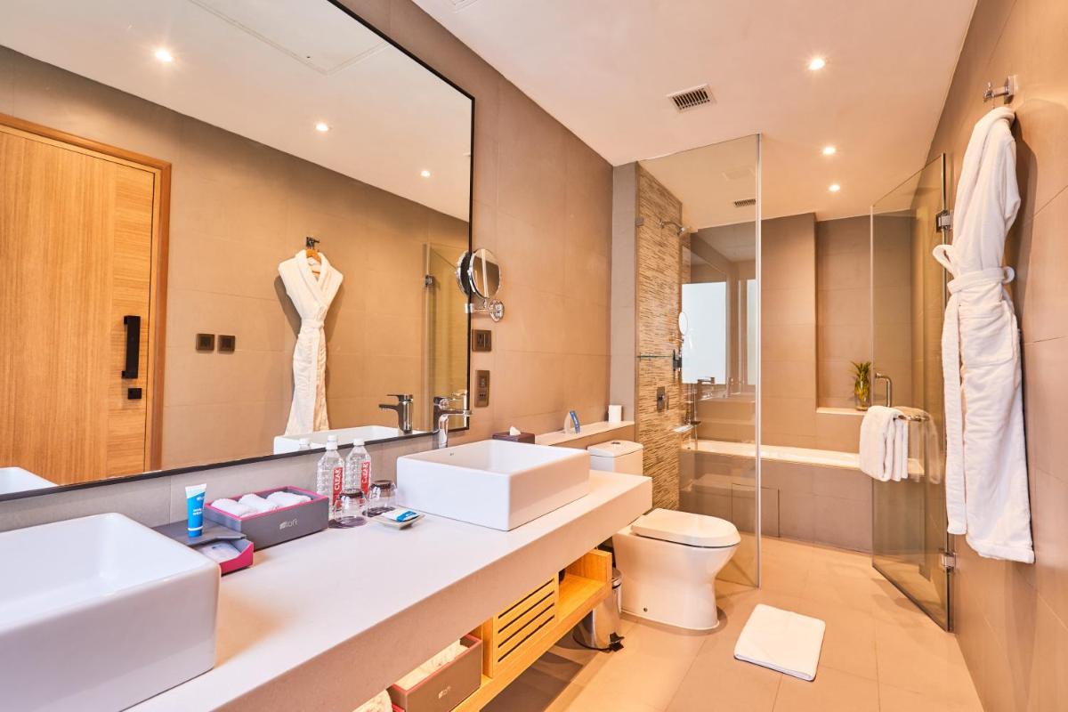 a bathroom with a sink and a toilet and a mirror at Aloft New Delhi Aerocity in New Delhi a bathroom with a sink and a toilet and a mirror at Aloft New Delhi Aerocity in New Delhi