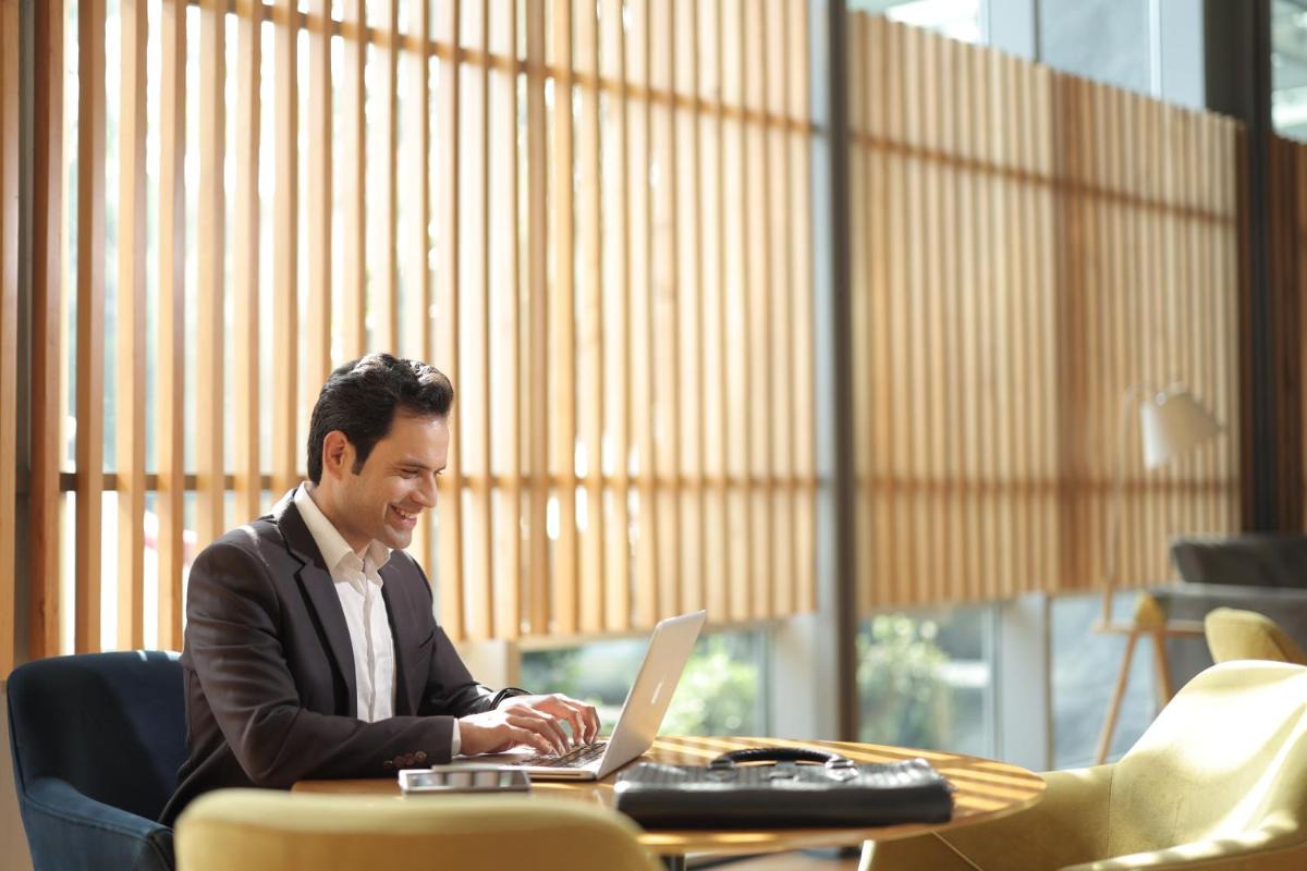 a man sitting at a table with a laptop computer at Aloft New Delhi Aerocity in New Delhi a man sitting at a table with a laptop computer at Aloft New Delhi Aerocity in New Delhi
