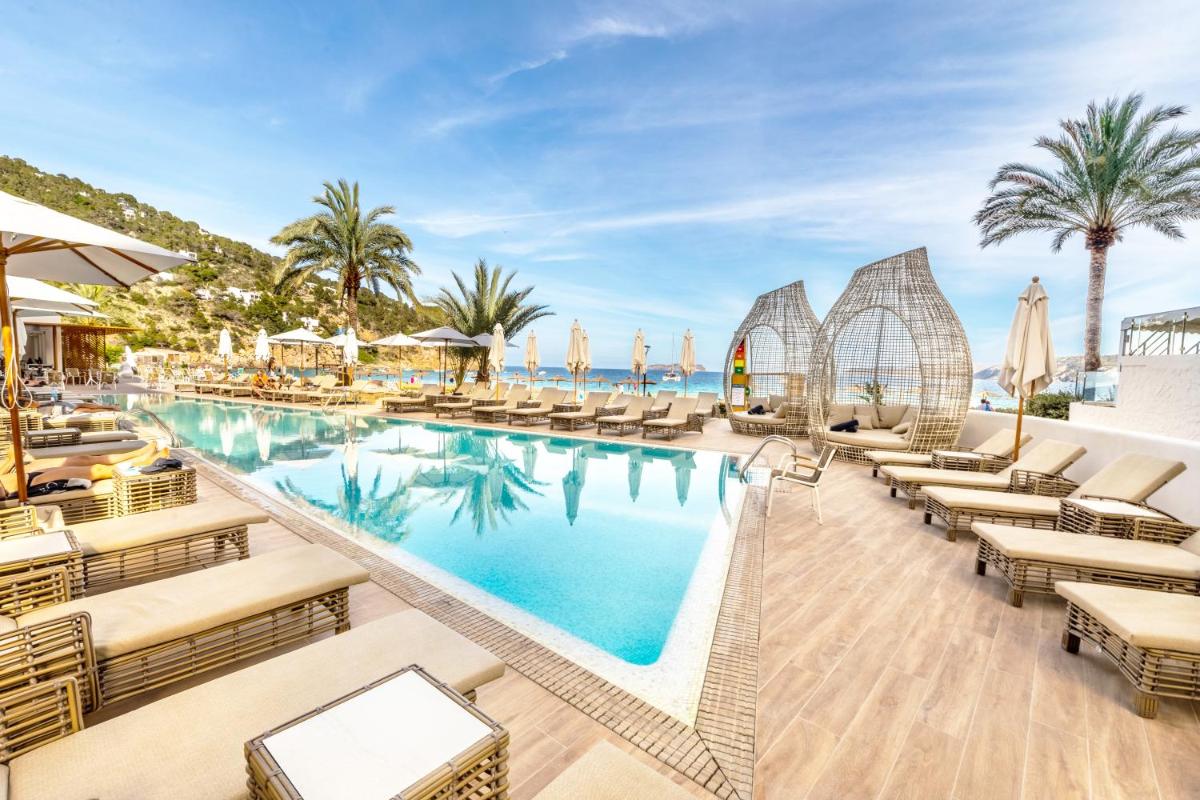 Una piscina tipo resort con tumbonas y palmeras. en El Somni Ibiza Dream Hotel by Grupotel, en Sant Joan de Labritja