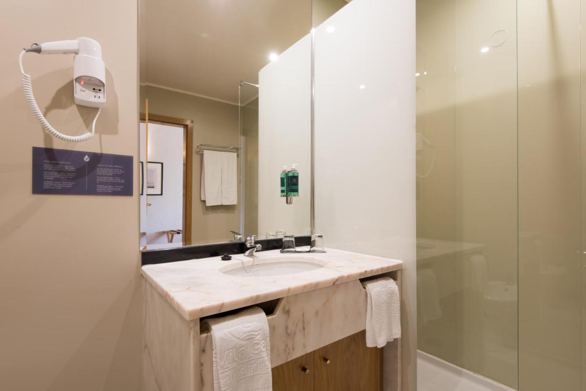 um banheiro com pia e box de vidro em Vila Gale Marina em Vilamoura