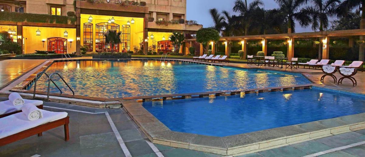 a large swimming pool with chairs and a building at Eros Hotel New Delhi, Nehru Place in New Delhi a large swimming pool with chairs and a building at Eros Hotel New Delhi, Nehru Place in New Delhi