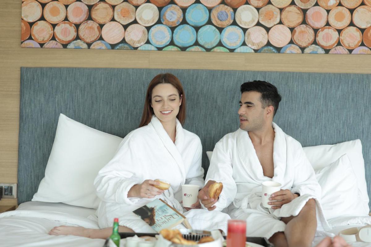 a man and woman in white robes sitting on a bed at Aloft New Delhi Aerocity in New Delhi a man and woman in white robes sitting on a bed at Aloft New Delhi Aerocity in New Delhi