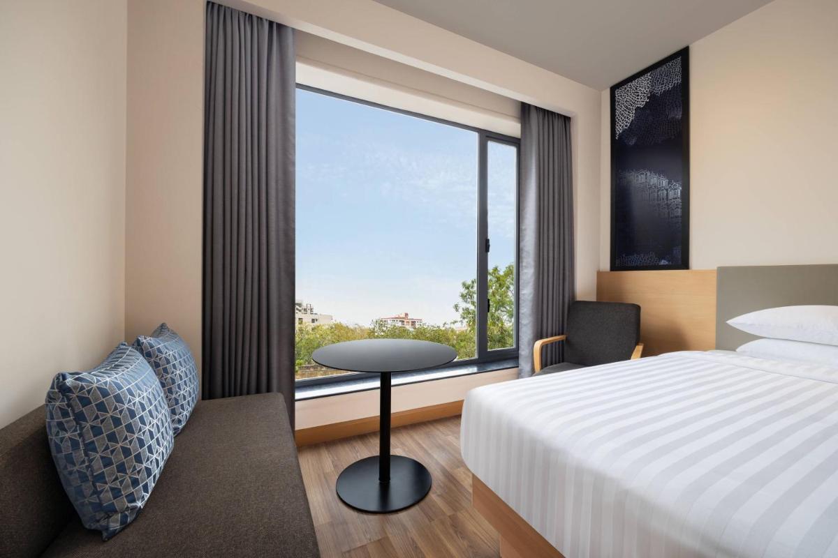 a hotel room with a bed and a large window at Fairfield by Marriott Jaipur in Jaipur