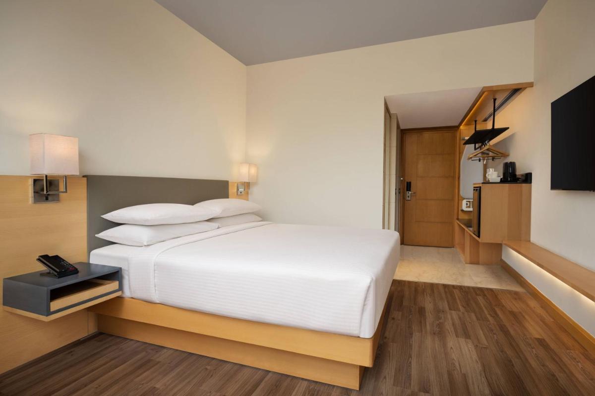 a bedroom with a white bed and a television at Fairfield by Marriott Jaipur in Jaipur