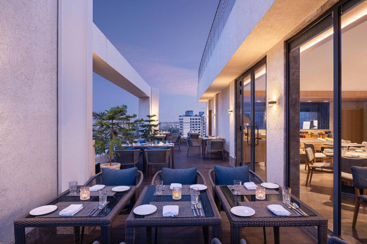a restaurant with tables and chairs on a balcony at Fairfield by Marriott Jaipur in Jaipur