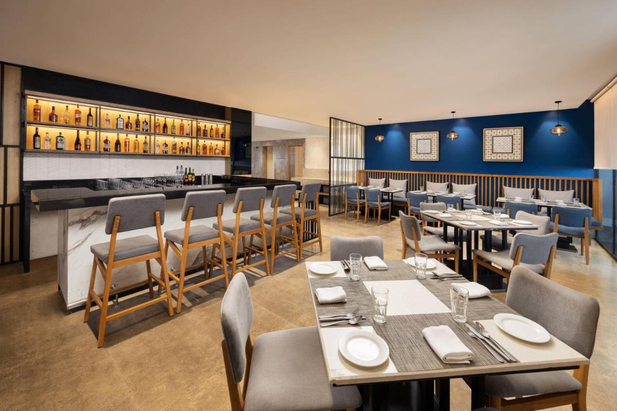 a restaurant with tables and chairs and a bar at Fairfield by Marriott Jaipur in Jaipur