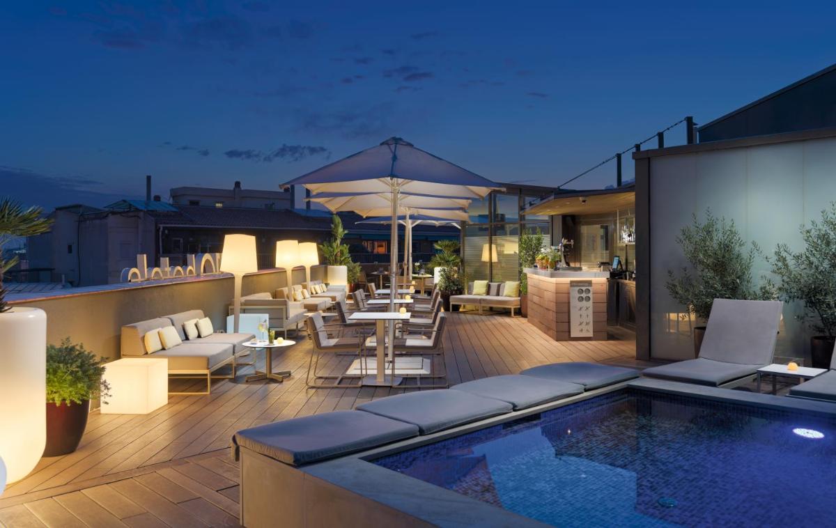 un patio en la azotea con piscina, mesas y sillas en H10 Casanova, en Barcelona