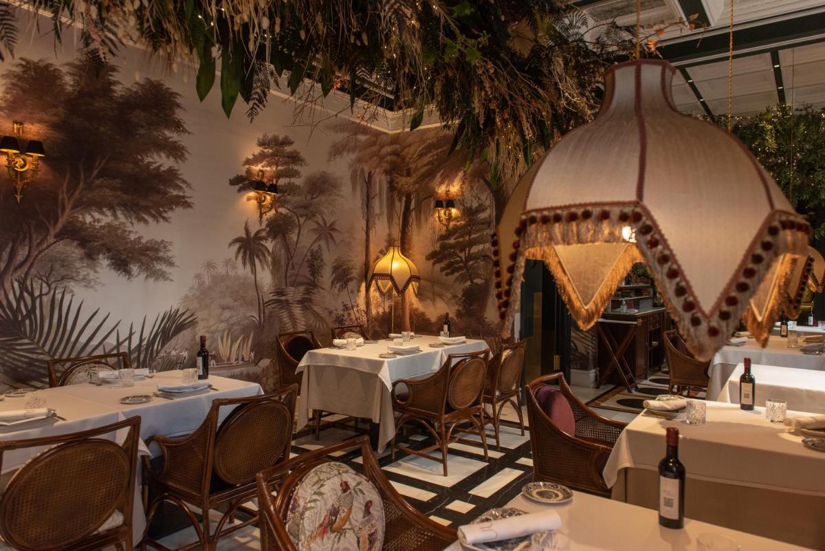 Un restaurante con mesas y sillas y un mural en la pared. en Hotel Casa Palacio María Luisa, en Jerez de la Frontera