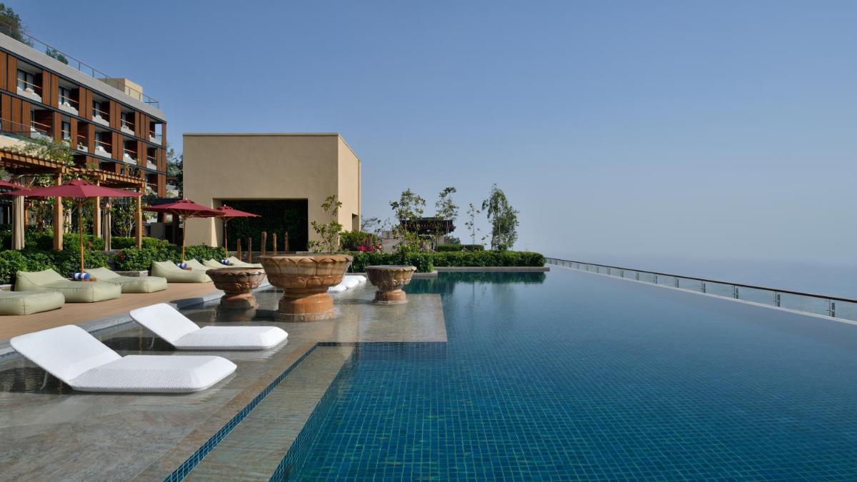 a swimming pool with white lounge chairs next to a building at The Westin Resort & Spa Himalayas in Rishīkesh