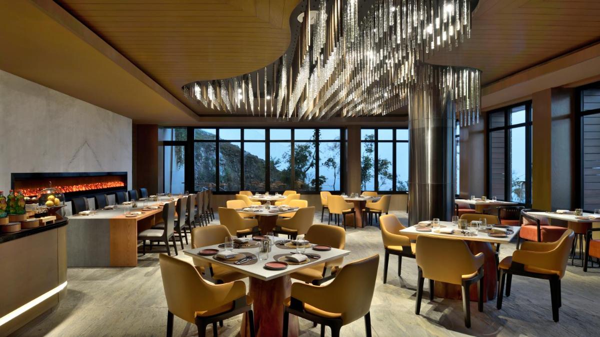 a restaurant with tables and chairs and a chandelier at The Westin Resort & Spa Himalayas in Rishīkesh