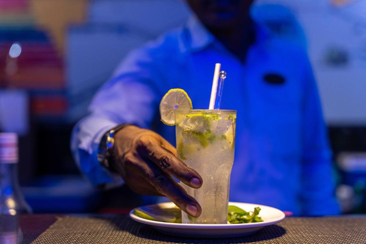a hand holding a drink with a plate of food at The Crown Goa in Panaji