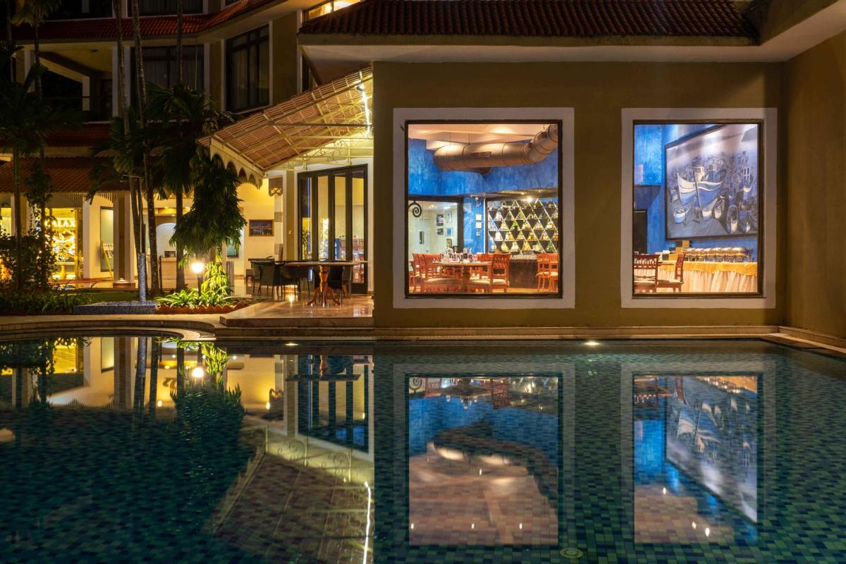 a house with a swimming pool at night at The Crown Goa in Panaji