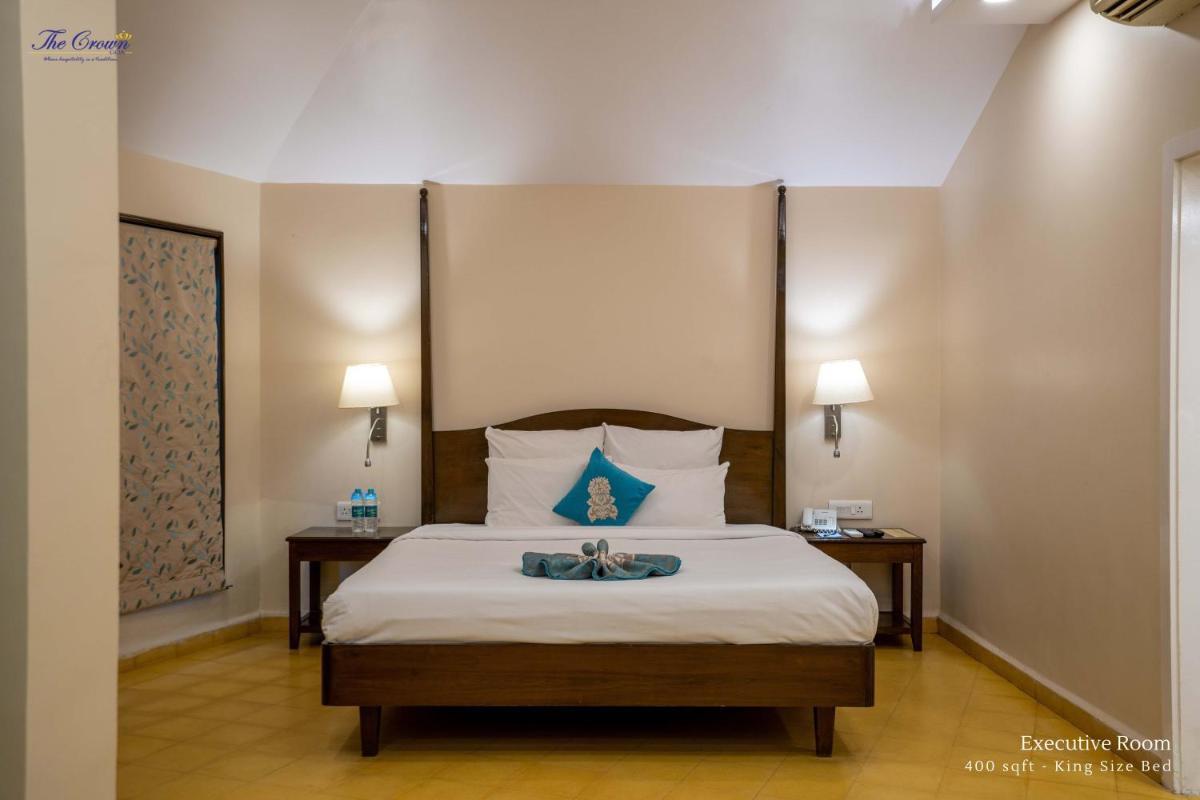 a bedroom with a large bed with two night stands at The Crown Goa in Panaji