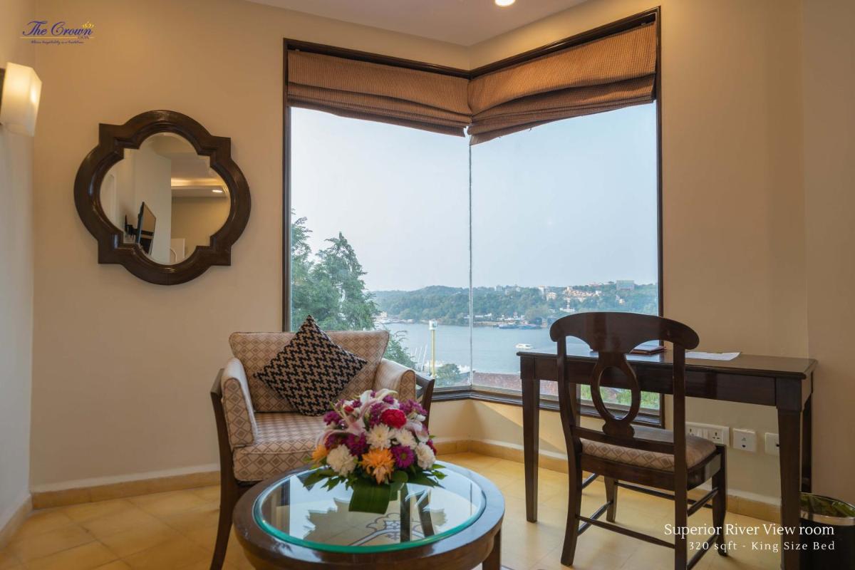a living room with a table and chairs and a window at The Crown Goa in Panaji