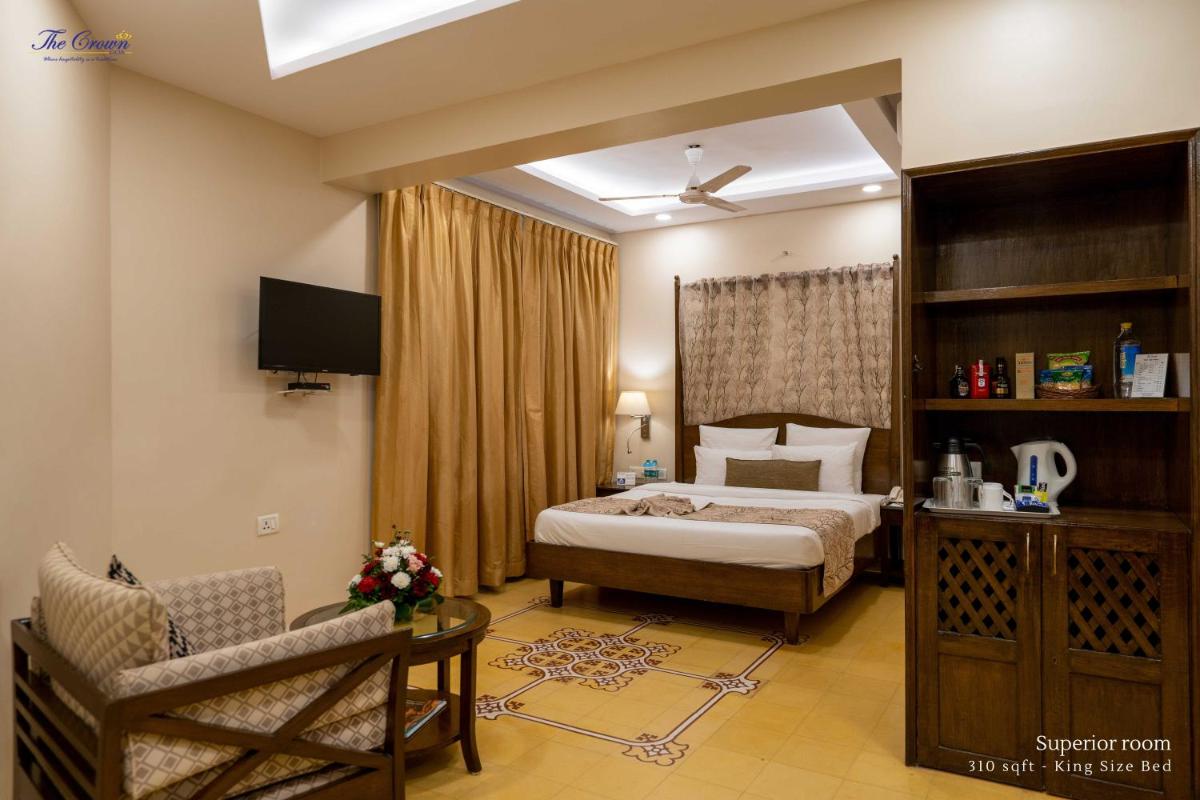 a bedroom with a bed and a chair and a television at The Crown Goa in Panaji