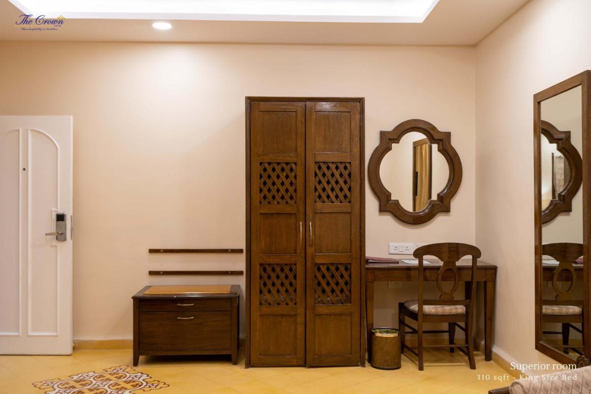a room with a mirror and a wooden cabinet at The Crown Goa in Panaji