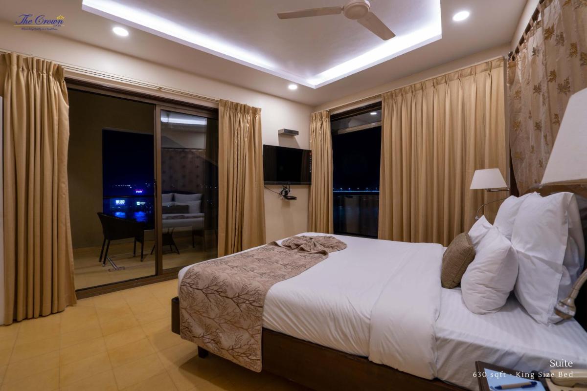 a bedroom with a bed and a large window with a view at The Crown Goa in Panaji