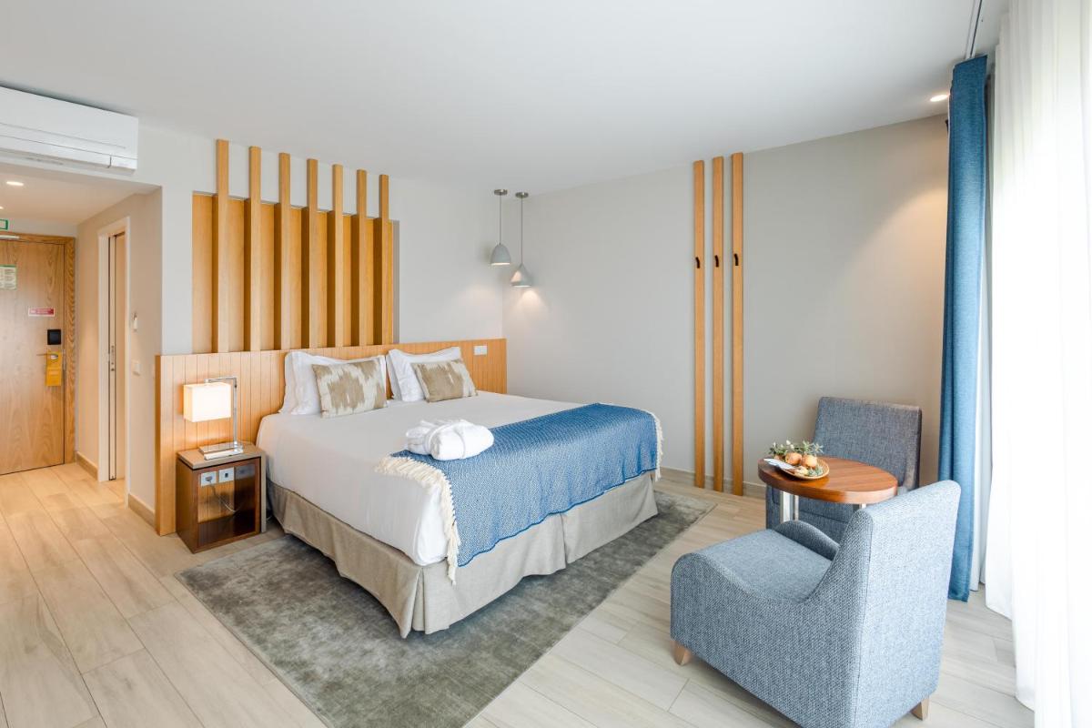 um quarto com uma cama e uma cadeira azul em Herdade dos Delgados em Mourão