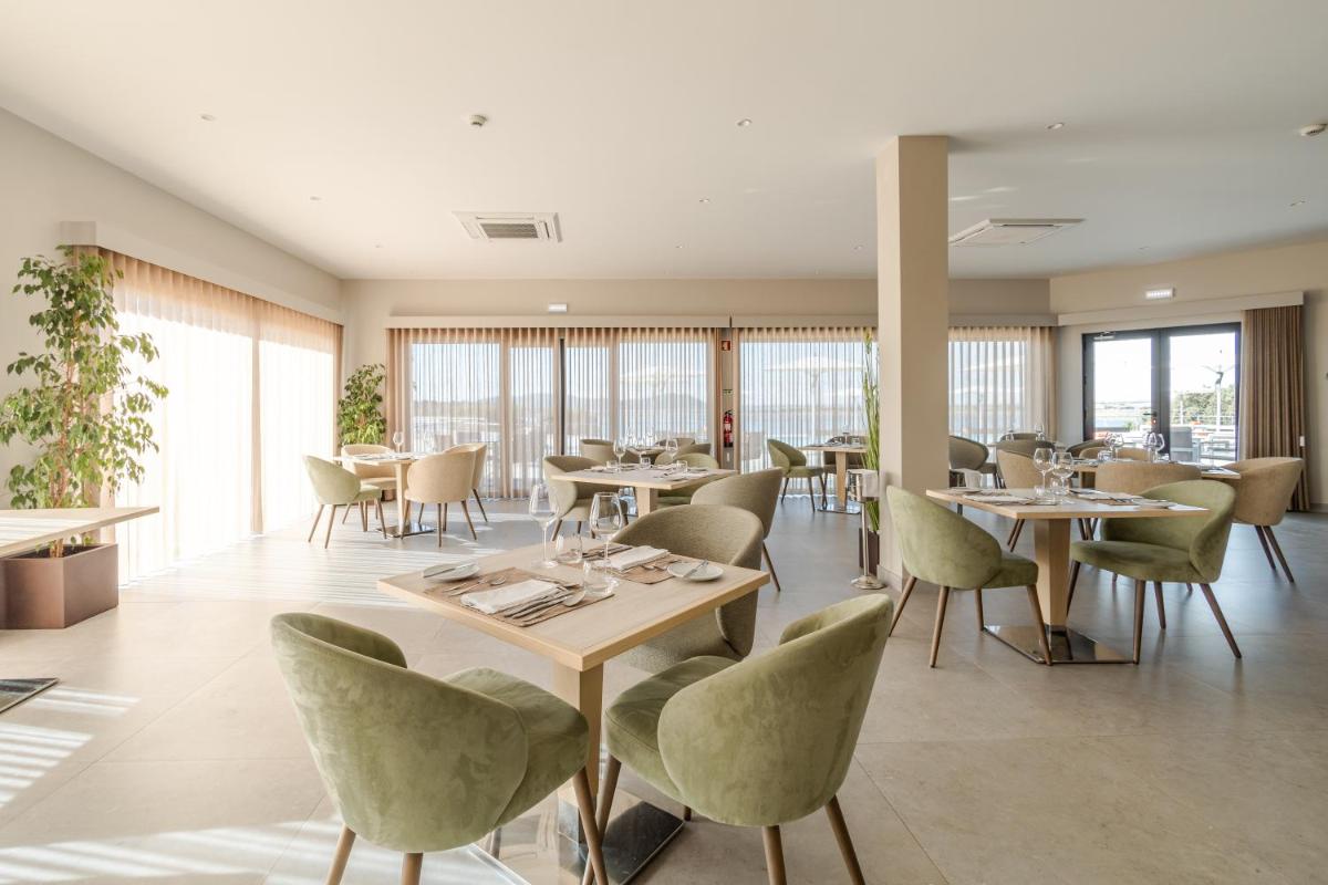 um restaurante com mesas, cadeiras e janelas em Herdade dos Delgados em Mourão