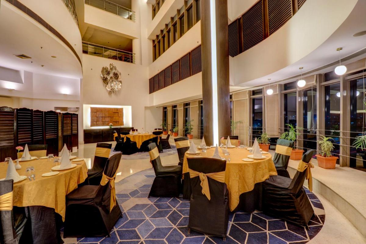 a restaurant with tables and chairs in a building at Sunday Hotel Jaipur in Jaipur