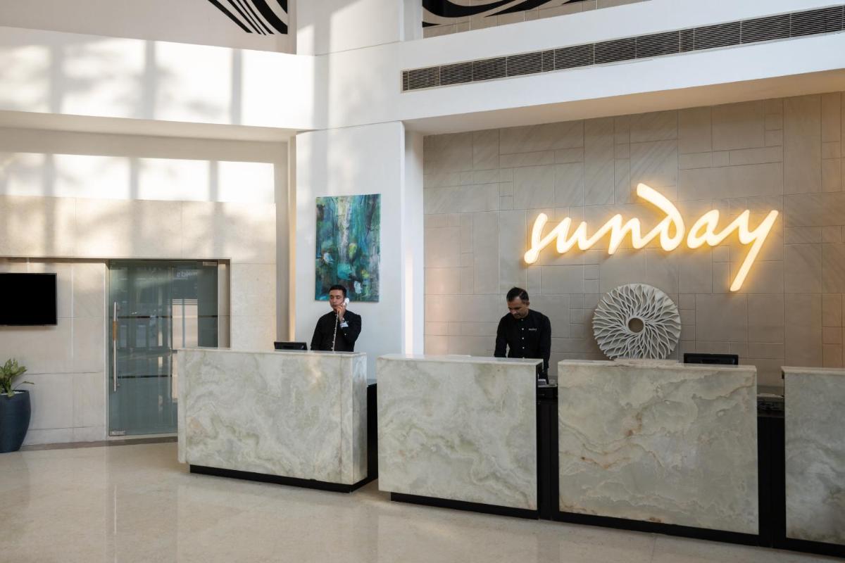 two men standing at a counter in a lobby at Sunday Hotel Jaipur in Jaipur