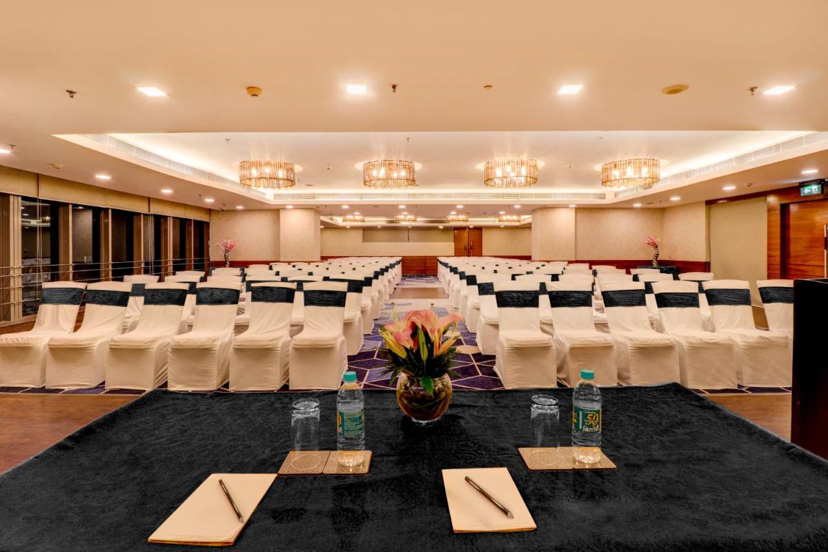 a banquet hall with white chairs and a table with napkins at Sunday Hotel Jaipur in Jaipur