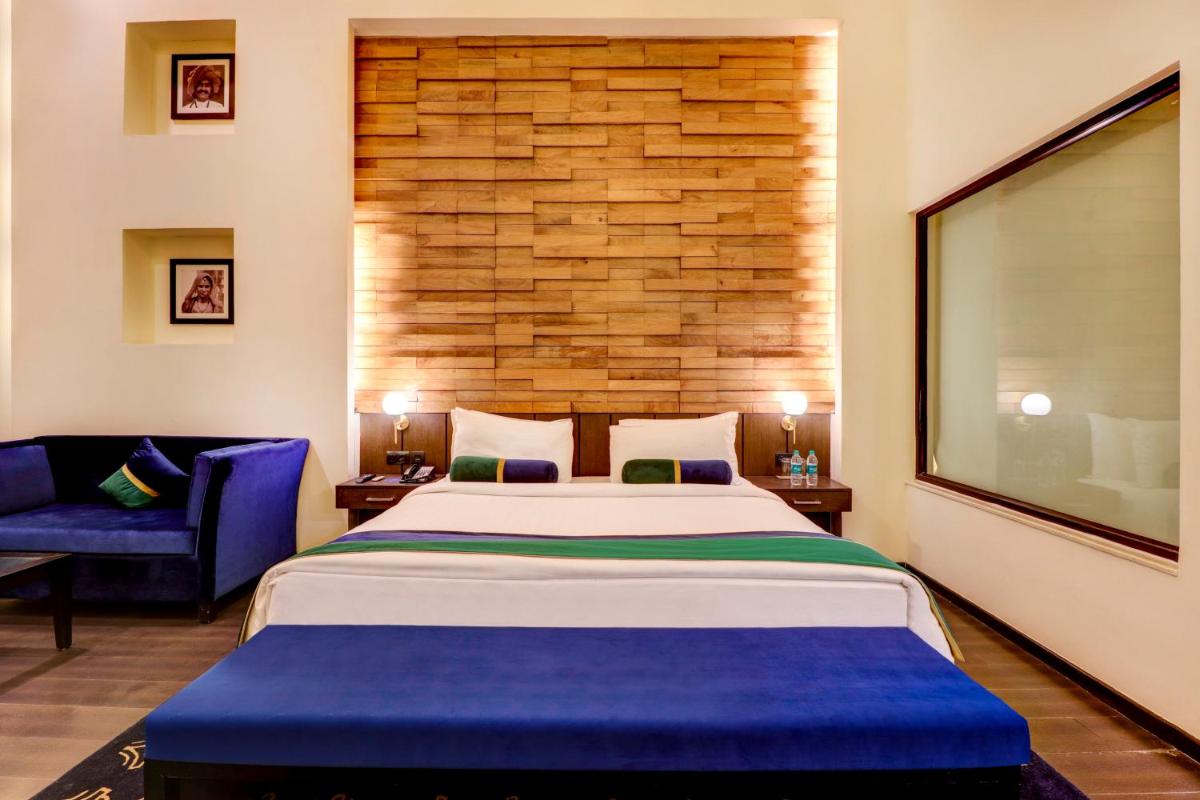 a bedroom with a large bed and a blue couch at Sunday Hotel Jaipur in Jaipur