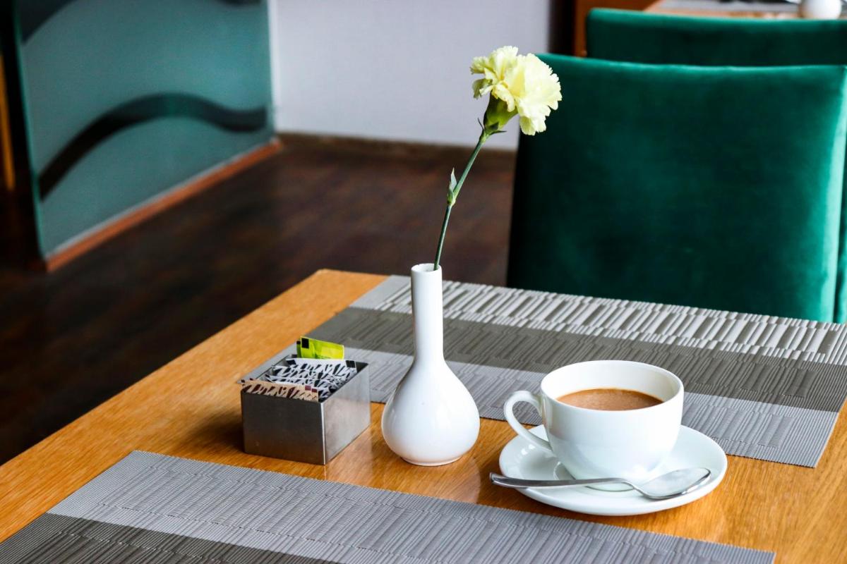 a table with a vase and a cup of coffee at Sunday Hotel Jaipur in Jaipur