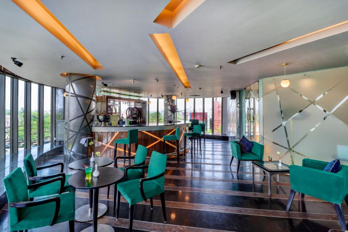 a room with green chairs and tables and a bar at Sunday Hotel Jaipur in Jaipur