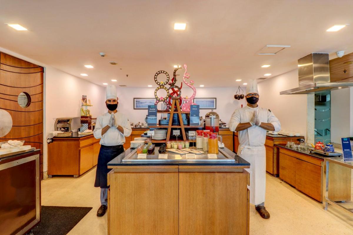 two chefs standing behind a counter in a kitchen at Sunday Hotel Jaipur in Jaipur