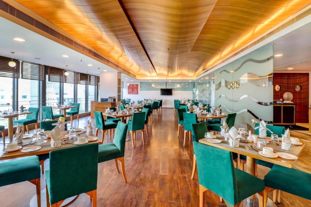 a restaurant with wooden ceilings and green chairs at Sunday Hotel Jaipur in Jaipur