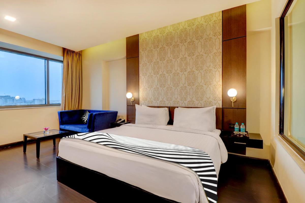 a hotel room with a large bed and a chair at Sunday Hotel Jaipur in Jaipur