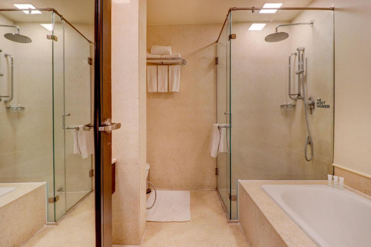 a bathroom with a shower and a tub and a toilet at Sunday Hotel Jaipur in Jaipur