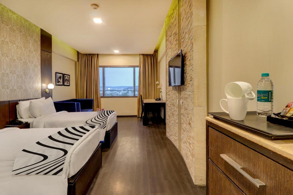 a hotel room with two beds and a television at Sunday Hotel Jaipur in Jaipur
